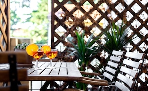 A wooden table with two glasses of amber liquid and a slice of orange.