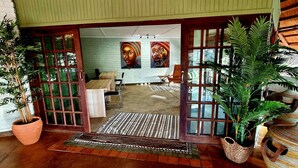 A room with a wooden door, a potted plant, a woven basket, and a tiled floor. - The Wallow Lodge (Victoria Falls)