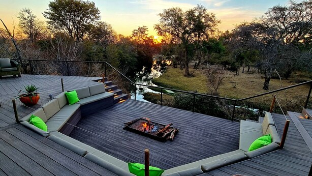 A deck with a fire pit and outdoor seating. - The Wallow Lodge (Victoria Falls)