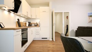 A modern kitchen with white cabinets, a wooden countertop, and a built-in oven. - Störtebeker 4 (Kellenhusen)