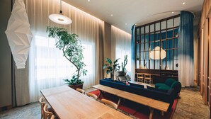 Una sala de estar moderna con una mesa de comedor de madera, un sofá azul y una planta grande en maceta.