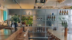 Una zona de bar con una barra larga, taburetes y estantes llenos de botellas.