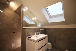 A modern bathroom with a skylight, a vanity with a mirror, and a toilet. - Störtebeker 8 (Kellenhusen)