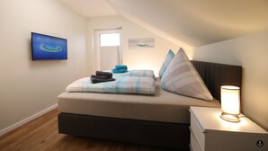 Quarto com cama, mesa de cabeceira com luminária, pintura na parede e janela.