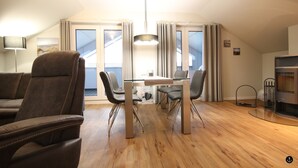 Uma sala de estar moderna com uma mesa de vidro, dois sofás de couro marrom e piso de madeira.