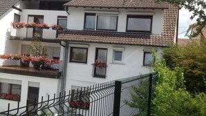 Un edificio de dos pisos con balcones decorados con macetas llenas de flores.