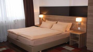 A hotel room with a large bed, two bedside tables, and a nightstand.