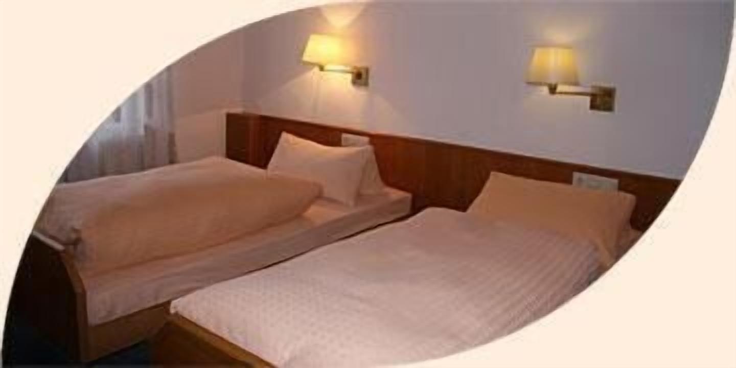 Een kamer met twee bedden, elk voorzien van een houten hoofdbord en een wandlamp.