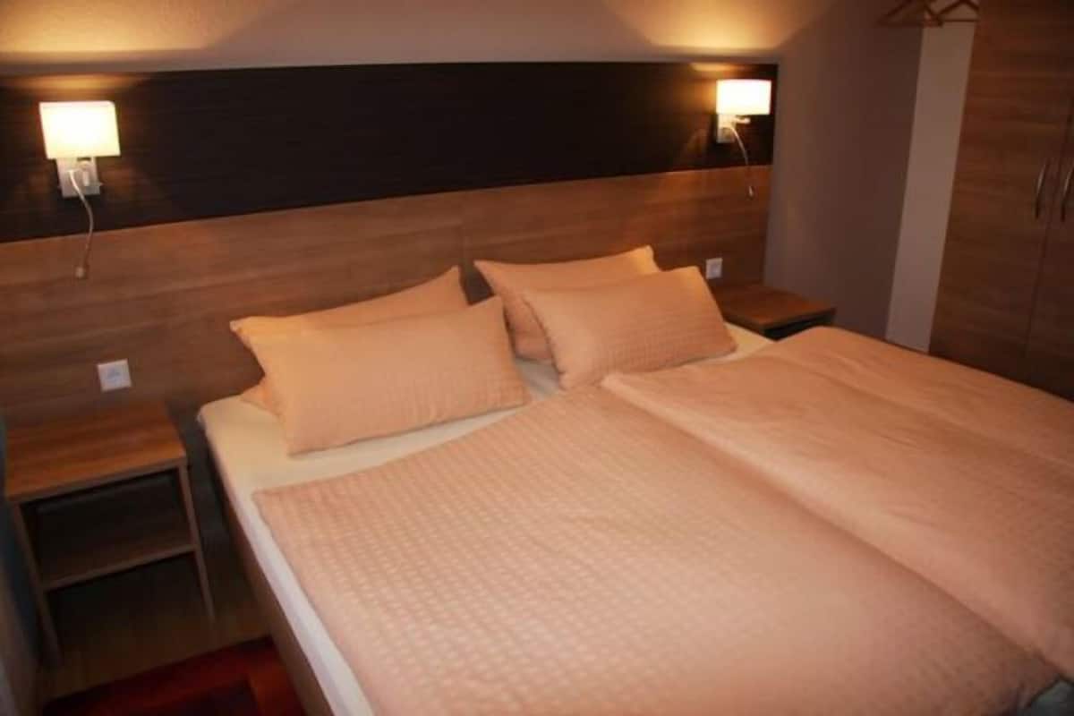 Un dormitorio con cabecera de madera, dos mesitas de noche y una cama con ropa de cama color beige.