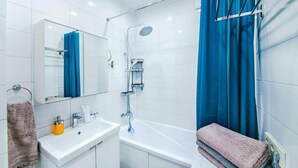 A modern bathroom with a white sink, mirror, and shower.
