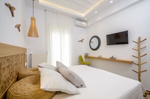 A modern hotel room with a bed, woven ottoman, wall-mounted TV, and a wooden headboard. - Beach Connection Naxos town (Naxos)