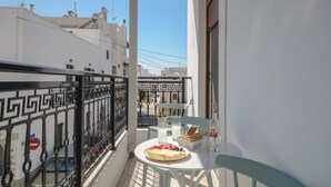 A balcony with a table set for two, a bottle of water, and a plate of food. - Beach Connection Naxos town (Naxos)