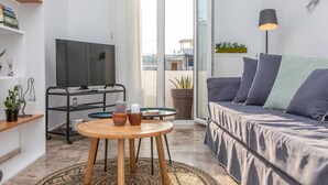 A modern living room with a sofa, a TV, a coffee table, and a bookshelf. - Beach Connection Naxos town (Naxos)