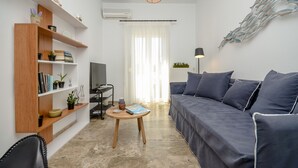 A modern living room with a sofa, a coffee table, and a bookshelf. - Beach Connection Naxos town (Naxos)