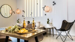 A modern dining area with a wooden table set for two, featuring a bottle of wine, a glass, and a floral arrangement. - Exclusive Studios Naxos Town (Naxos)