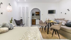 A modern, well-lit room with a bed, a sofa, a dining area, and a kitchen visible through an archway. - Exclusive Studios Naxos Town (Naxos)