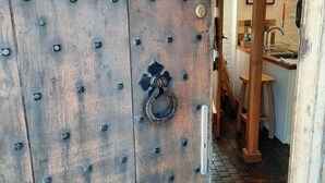 Een houten deur in rustieke stijl, voorzien van metalen knoppen en een decoratieve metalen handgreep.