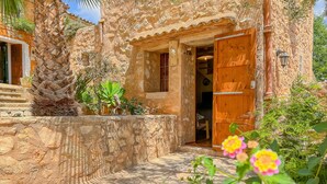 A rustic stone building with a wooden door and a small porch area. - Charming Villa Can Xesquet (Felanitx)