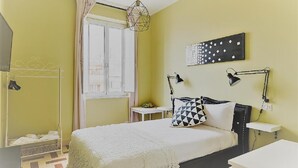 A bedroom with a bed, bedside lamps, a window, and a wall art piece.