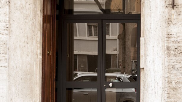 A building entrance with a double door, a wooden door on the left, and a metal door on the right.