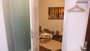 A hallway leading to a living area with a sofa, a small table, and a painting on the wall. - Apartment Goethe (Jena)