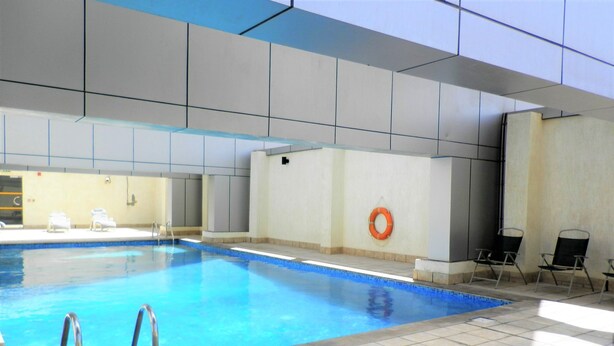 Una piscina interior con paredes de azulejos, un flotador salvavidas y sillas de descanso.