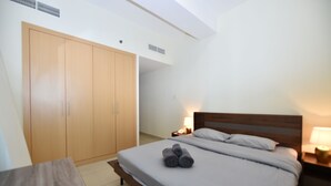Un dormitorio con cama, mesitas de noche, armario y una pequeña mesa.