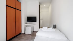 A hotel room with a bed, a TV, a wardrobe, and a desk with a lamp. - Miga Hotel Grado Centro (Grado)