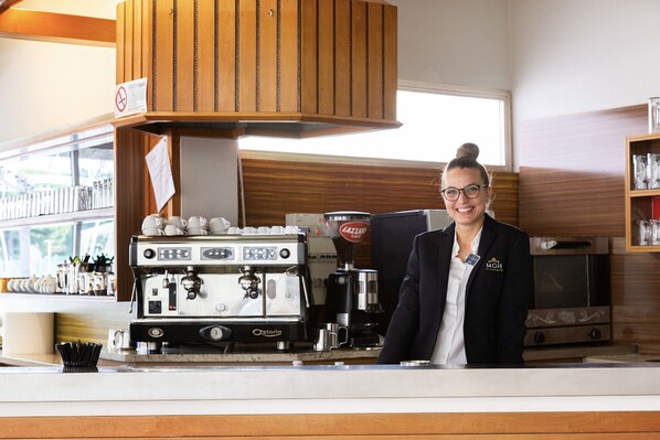 A coffee shop counter with an espresso machine, a coffee grinder, and a branded coffee cup.