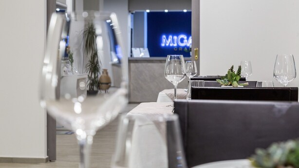 A modern dining area with tables set for two, featuring clear glassware and a minimalist decor. - Miga Hotel Grado Centro (Grado)