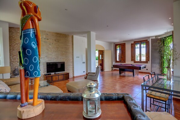 A spacious living area with a pool table, a television, and a sofa.