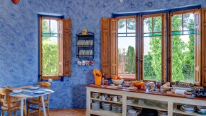 Eine Küche mit blauen Wänden, Holzschränken und einem Essbereich mit Tisch für vier Personen.