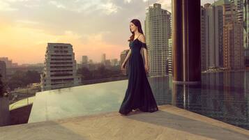 A woman standing by a modern pool with a cityscape view.