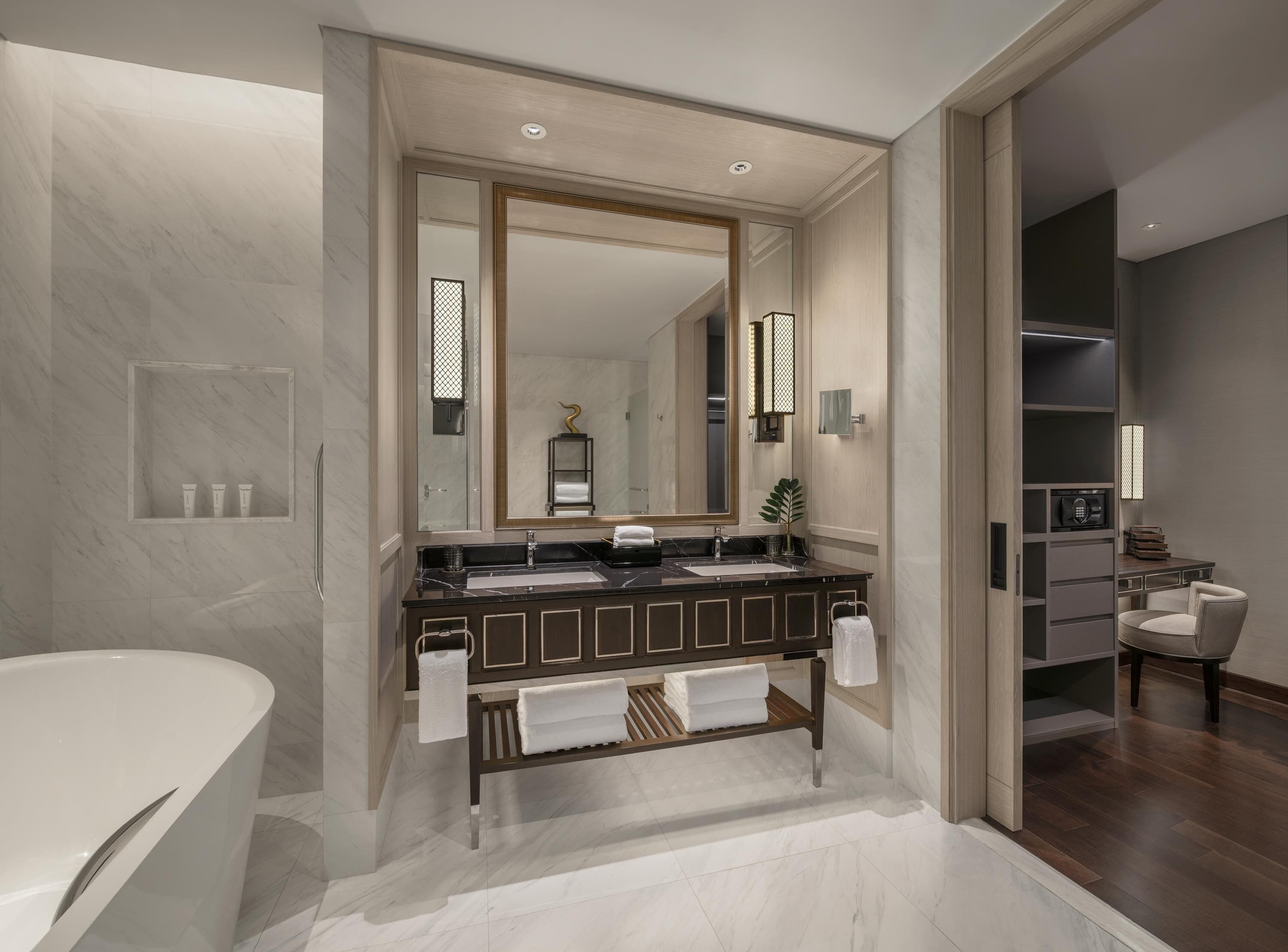 A modern bathroom with a double sink vanity, a large mirror, and a bathtub.