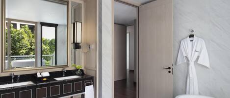 Un baño moderno con un espejo grande, lavamanos dobles, una bañera y una bata colgada en la pared.