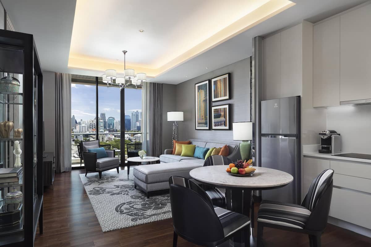 Una sala de estar moderna con vistas a la ciudad, un comedor con mesa redonda y una cocina con electrodomésticos de acero inoxidable.