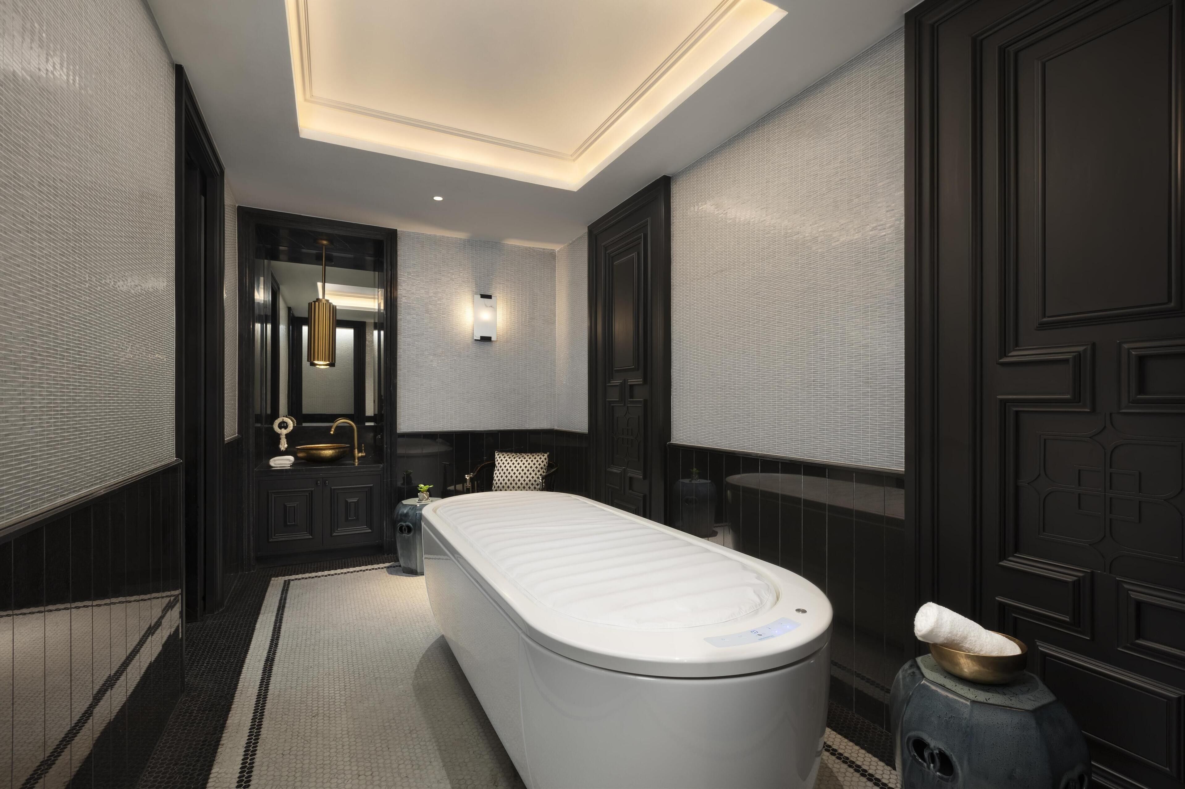 A modern bathroom with a freestanding bathtub, a vanity with a mirror, and a wall-mounted light fixture.
