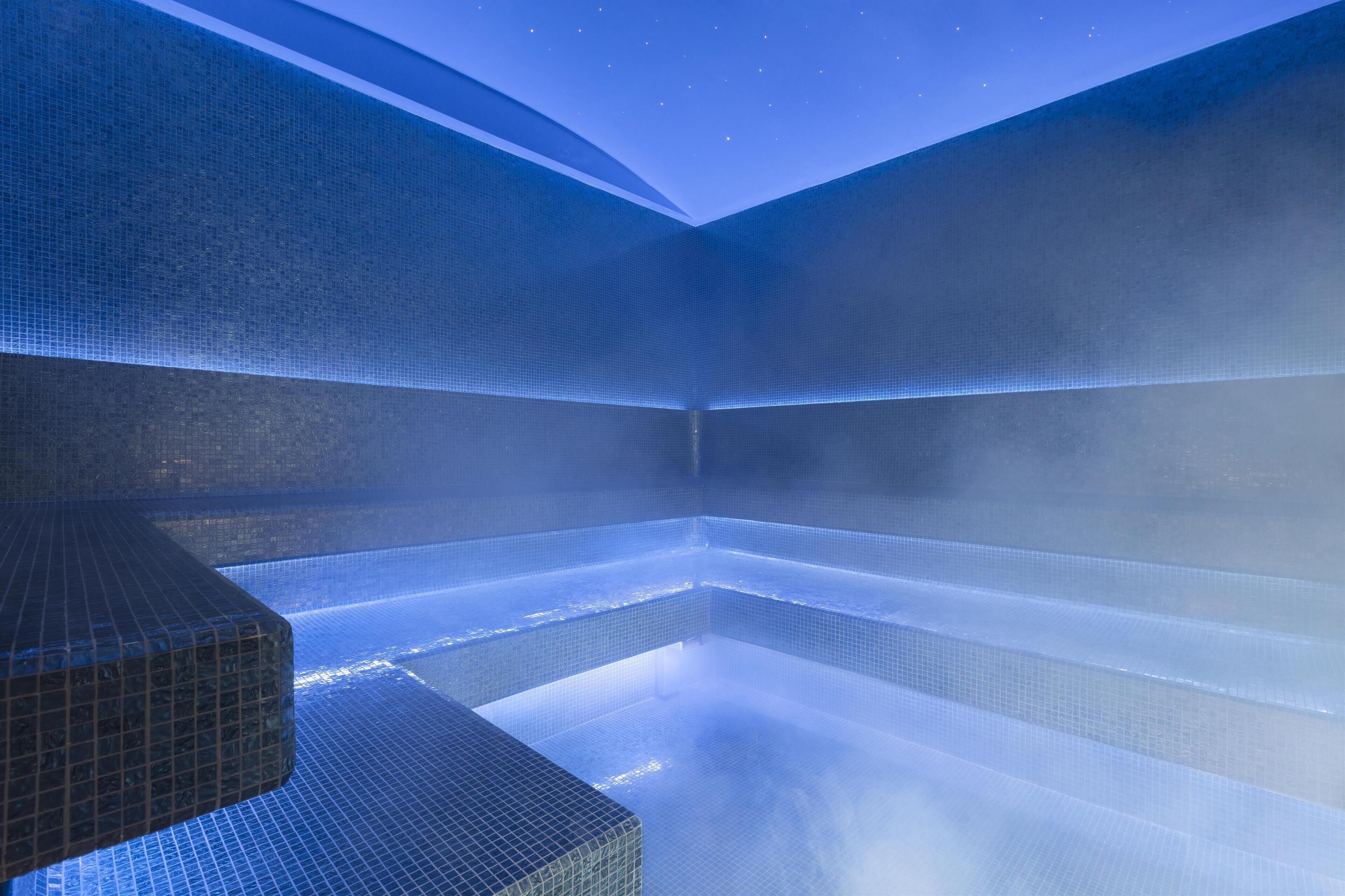 A modern spa with a geometric tiled design and a visible steam feature.