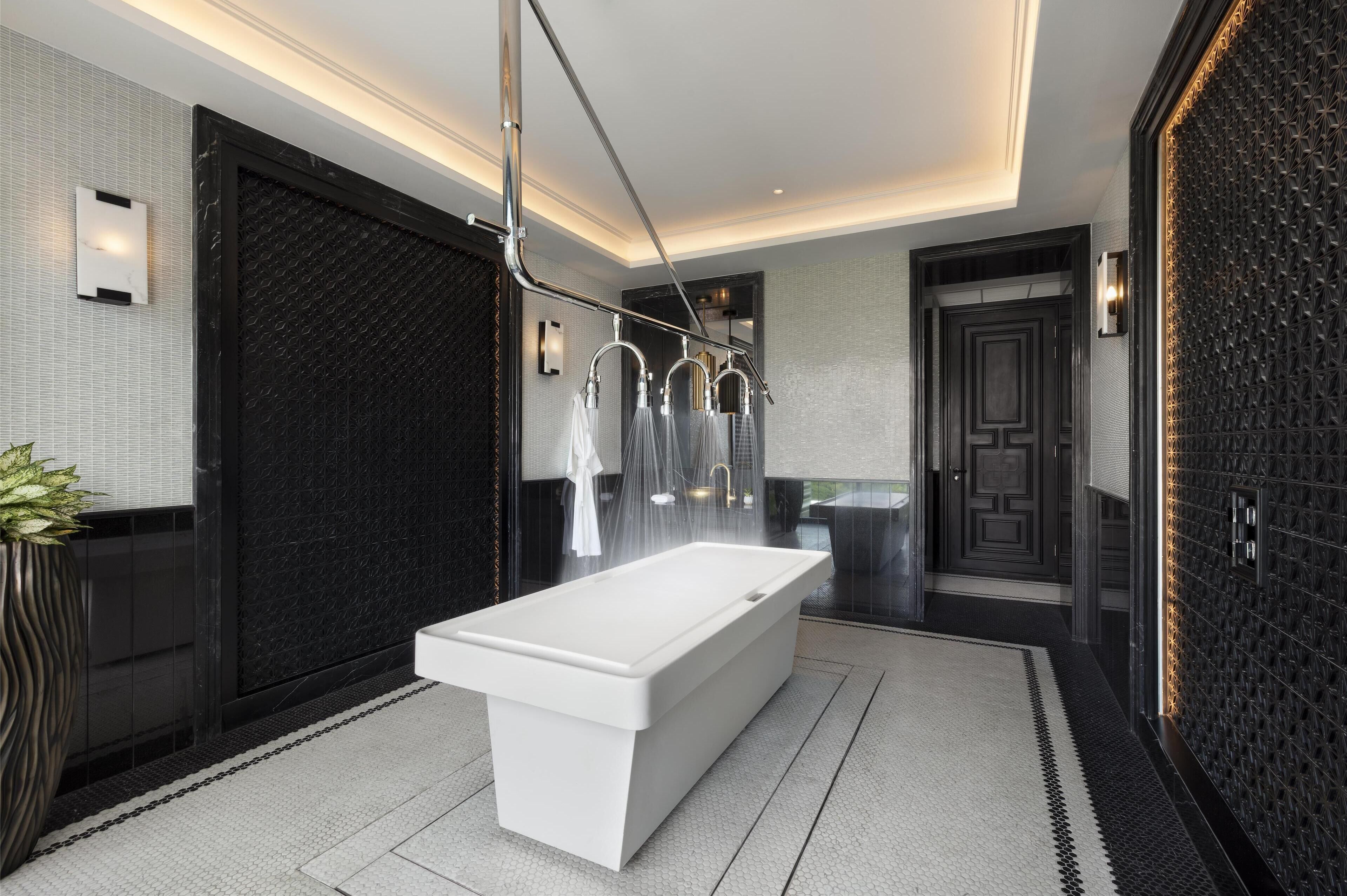 A modern bathroom with a large white bathtub, a black textured wall, and a sleek design.