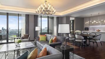 Una sala moderna con sofá, mesa de centro y comedor. Hay un ventanal con vista a la ciudad.