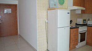 A kitchen with a refrigerator, microwave, oven, and wooden cabinets.