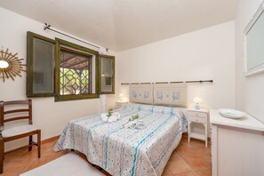 A bedroom with a bed, a chair, a desk, and a window with shutters. - COSTA SMERALDA APARTMENT in semi-detached villa with sea view in Cannigione alta (ARZACHENA)