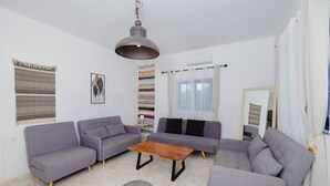 A modern living room with grey sofas, a wooden coffee table, and a hanging pendant light. - Beachfront Cabana @ EcoBeach Hotel (Gennadi)