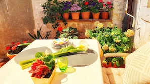 A cozy outdoor seating area with a table set for two, surrounded by potted plants and flowers. - Heart of the City Apartments (Dubrovnik)