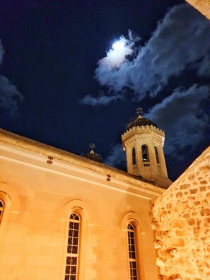 Un edificio con ventanas de arco y una torre con cúpula, bajo un cielo nocturno con luna visible.