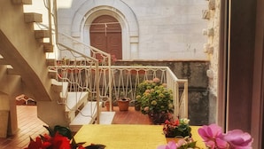 A courtyard with a staircase leading to a door, surrounded by potted plants and flowers. - Heart of the City Apartments (Dubrovnik)