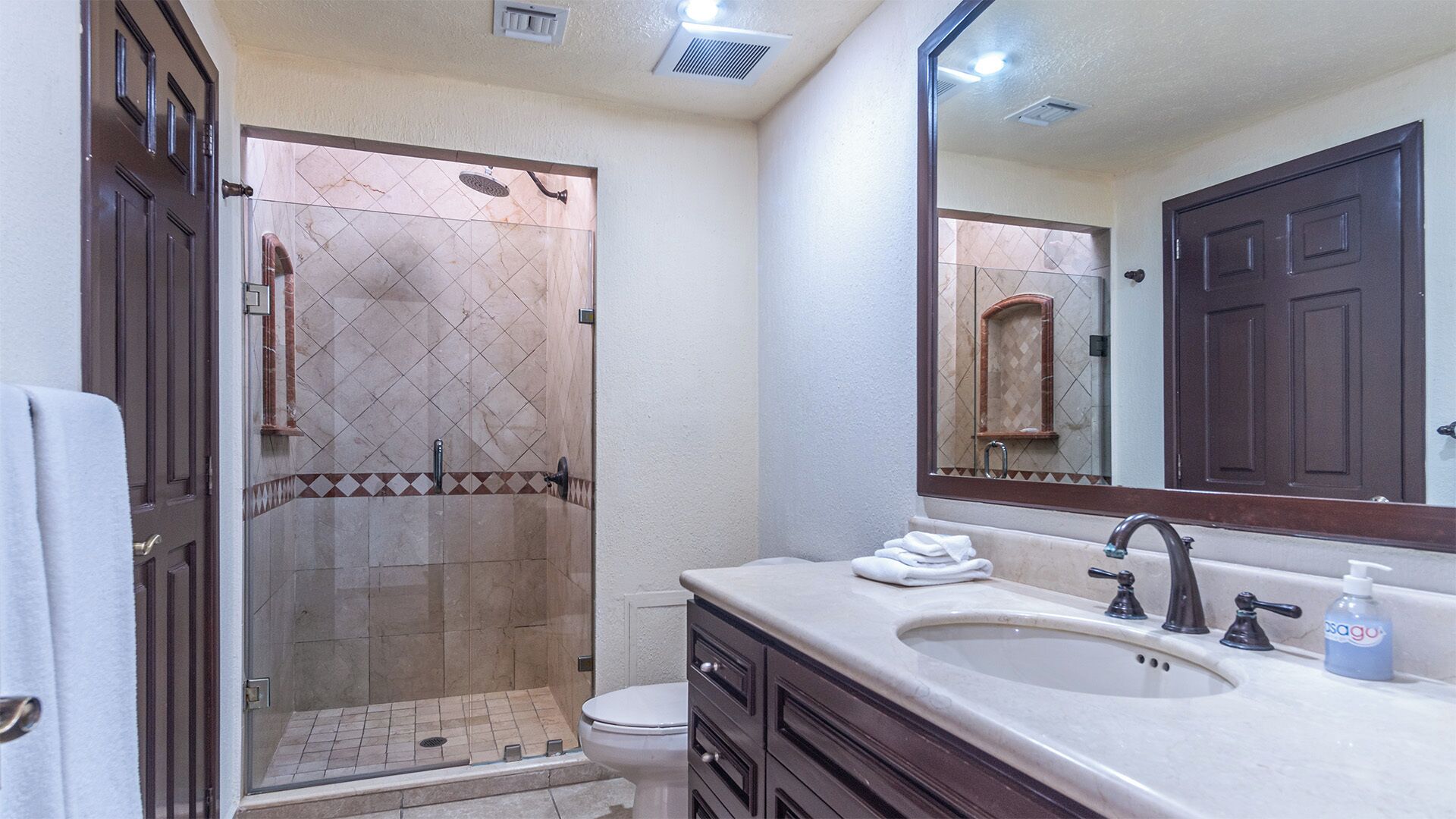 Une salle de bain équipée d’une douche, de toilettes, d’un lavabo et d’un grand miroir.