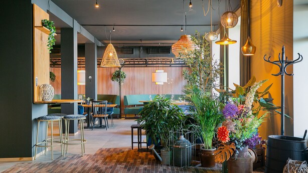 A modern interior with brick flooring, wooden accents, and a variety of plants. - Fletcher Hotel-Restaurant Marktstad-Schagen (Schagen)