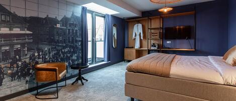 A modern bedroom with a large bed, a seating area, a TV, and a cityscape mural.