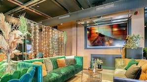 A modern lounge area with a green sofa, a coffee table, and decorative plants. - Fletcher Hotel-Restaurant Marktstad-Schagen (Schagen)